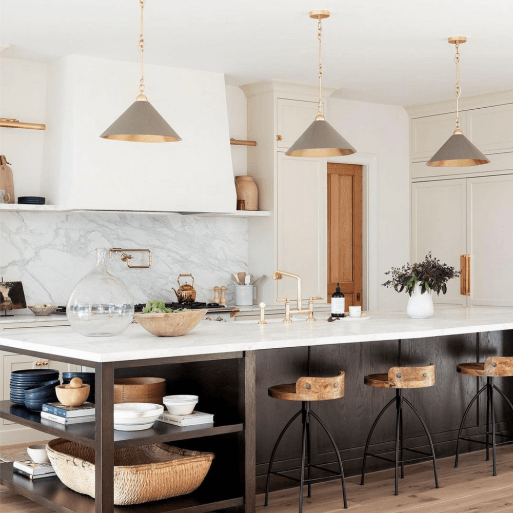 Marble kitchen with brass pendants and a walnut island.
